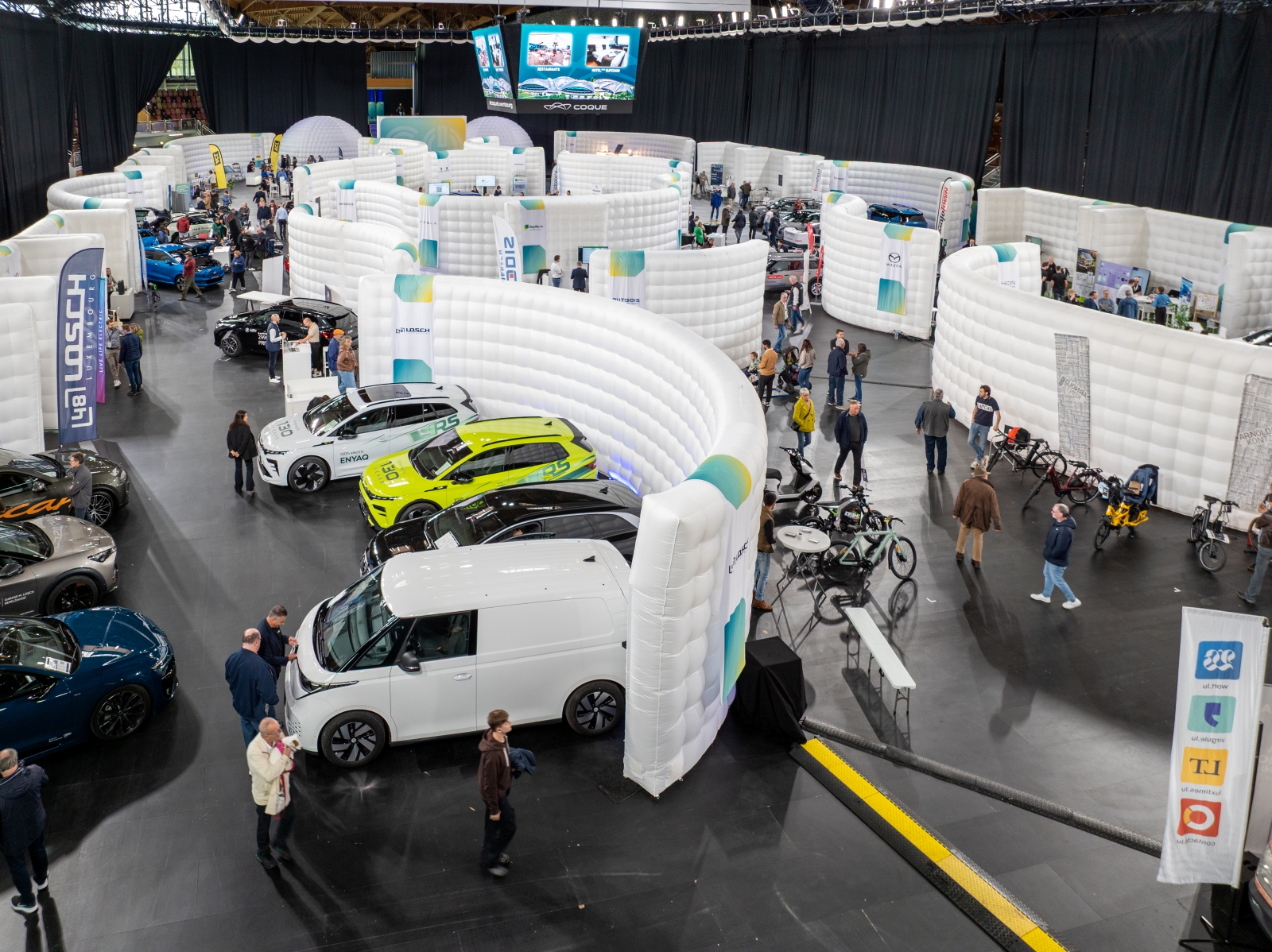 Vue aérienne de l’exposition GO Electric Day à la Coque, présentant plusieurs stands gonflables, des voitures électriques exposées et des visiteurs circulant entre les allées.